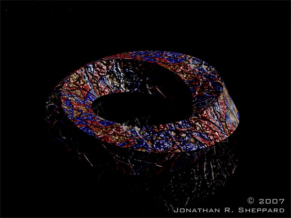 A twisted stone-like ring with red and blue flecks.